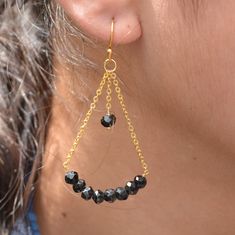 a close up of a person wearing some kind of gold earring with black beads