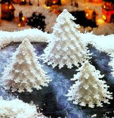 three snow covered trees sitting on top of a table