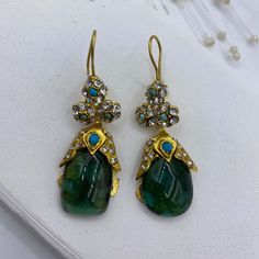 This fancy princess emerald statement ottoman drop earrings are inspired from sultan earrings in Topkapi museum. The similiar version can be seen in Topkapı İstanbul. Beautiful embellishments with blue turquoise and zircon are used on the top and joined tear drop emerald gemstone. The flower design decorated with zircon and turquoise below the kidney ear wire continues to tear drop shape emerald gemstone. It is a unique piece. Brass is plated with 24K gold micron which doesn't make color fading for years.  Handmade earrings Materials: 24K Gold plated brass, Gemstone: Emerald, zircon and turquoise Location: Earlobe Closure: Kidney ear wires Style: Tear drop Length: 5,5 cm / 2,16 inches Weight:15 g / 0,52 oz Traditional Green Jeweled Earrings, Traditional Green Earrings With Jewels, Traditional Emerald Drop Earrings, Traditional Emerald Earrings For Party, Green Jeweled Teardrop Earrings, Statement Ottoman, Green Stone Earrings, Earrings Fancy, Tear Drop Earrings