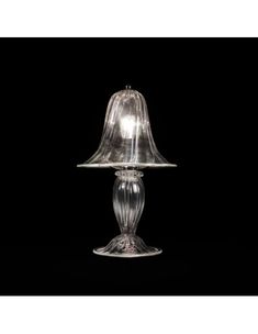 a glass table lamp with a clear shade on the base and a black back ground