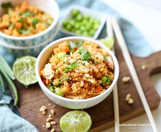 two bowls filled with rice and vegetables next to chopsticks on a cutting board