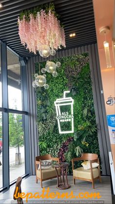 the inside of a coffee shop with pink flowers and greenery hanging from the ceiling