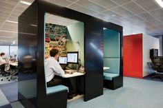 an office cubicle with people working on computers and sitting at desks in it