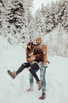 two people in the snow holding each other and one person has their feet up to his chest