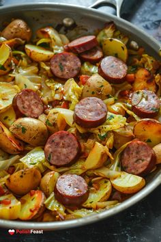 a pan filled with sausage and potatoes on top of a table