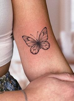 a woman's arm with a small butterfly tattoo on the left side of her arm