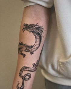 a woman's arm with a dragon tattoo on the left side of her arm