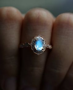 a woman's hand holding a ring with a blue stone in it