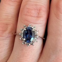 a woman's hand with a ring on it and a blue stone in the middle