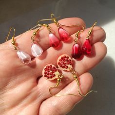 Set of unique, elegant pomegranate seed earrings. Fruit seed in ruby red, pink rose and crystal white colors or half fruit charm with tiny seeds inside. Finished with gold. Minimalist, memorable dangle earrings #pomegranateearrings #pomegranateseed #seedearrings #pomegranatejewelry #pomegranatelover #minimalistearrings #redseed #redpomegranate #whitegoldearrings #cutetinyearrings Pomegranate Seed Jewelry, Snow White Earrings, Pomegranate Accessories, Persephone Design, Pomegranate Aesthetic, Ruby Aesthetic, Fruit Accessories, Interesting Earrings, Cottagecore Earrings