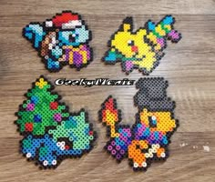 four pieces of perler bead art sitting on top of a wooden table