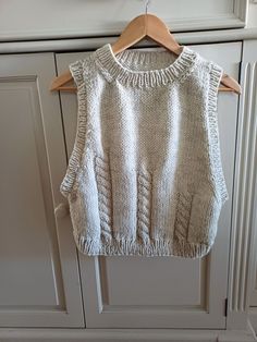 a white sweater hanging on a wooden hanger