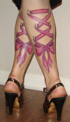 the legs and ankles of a woman with tattoos on her body are covered in pink ribbons