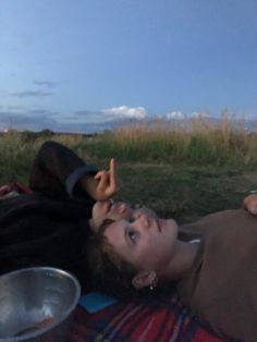 a woman laying on top of a blanket next to a metal bowl