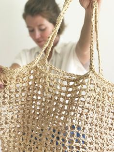 a woman is holding up a crocheted bag