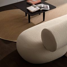 a white couch sitting on top of a wooden floor next to a black coffee table