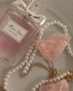 a bottle of perfume sitting on top of a table next to pearls and a necklace