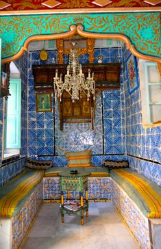 an ornate room with blue and yellow tiles on the walls, chandelier hanging from the ceiling