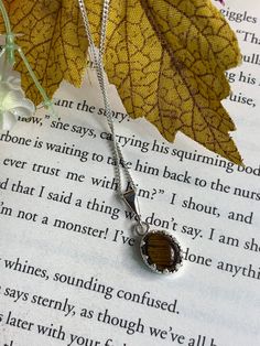 Tigers eye stone hand set in a sterling silver mount.  Hangs on an 18 inch sterling silver chain. Pendant measures approximately 6.5mm by 8.4mm  The stone is a beautiful earthy brown shade with stripes of golden brown throughout  Both necklace and pendant are hallmarked Sterling silver Sterling Silver Brown Round Pendant Necklace, Brown Sterling Silver Round Pendant Necklace, Brown Gemstone Round Pendant Jewelry, Sterling Silver Brown Necklace For Gift, Elegant Brown Sterling Silver Necklace, Adjustable Brown Sterling Silver Necklaces, Adjustable Brown Sterling Silver Necklace, Sterling Silver Necklace With Amber Round Pendant, Brown Polished Jewelry As Gift