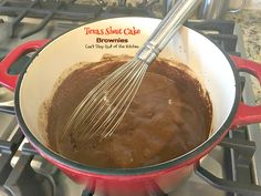 a red pot filled with chocolate batter on top of a stove