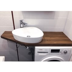 a white bowl sitting on top of a wooden counter next to a washer and dryer