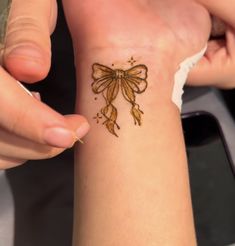 a woman is getting her tattoo done on her wrist with gold glitters and bows