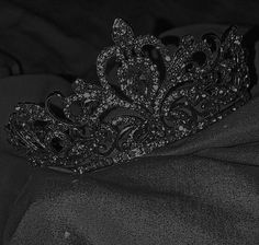 a black and white photo of a tiara on top of a cloth material background