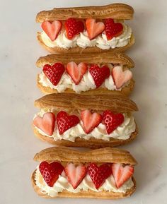 four sandwiches with strawberries and whipped cream on them are arranged in the shape of hearts