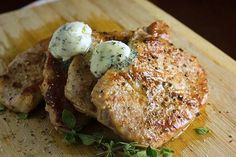 some food is sitting on a cutting board with green garnishes and herbs