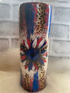 a blue and red vase sitting on top of a white fur covered floor next to a brick wall