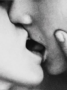 a man and woman kissing each other with their noses close to one another, black and white photograph