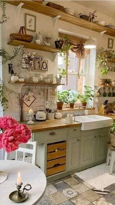 a kitchen filled with lots of green cupboards and white dishes on top of wooden shelves