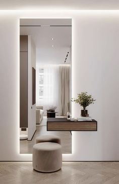 a white living room with an ottoman and table in the center, along with a large mirror on the wall