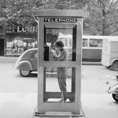 a woman standing in front of a telephone booth