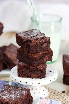 chocolate brownies stacked on top of each other with a glass of milk in the background