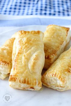 four pastries on a white plate sitting on a blue and white checkered table cloth