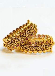 Pothi - Gold Kada Bracelet for Women w/ Cluster Gold balls & Ruby Stone Setting Stone Setting: Ruby Finish: Gold Plated Composition: Metal Alloy Cluster gold beaded bangle for desi women. This is a Kada style bangle set that is the perfect accessory for any Indian outfit. Stunning ruby gemstones adorn this pair of bangles. Elaborated with traditional temple jewelry style beads of gold on these bangles. These women's Kada bracelet set has been handcrafted by artisans & designed by team B Anu with Gold Beads Bracelets For Festivals, Gold Beaded Bracelets For Festive Occasions, Festive Gold Beaded Bracelet, Gold Beaded Bracelets For Diwali, Traditional Gold Beaded Bracelets For Celebration, Festive Hand-set Gold Bracelet In Temple Jewelry Style, Hand Set Gold Bracelet Temple Jewelry For Festive Occasions, Temple Jewelry Style Hand Set Gold Bracelet For Festive, Gold Bracelets With Latkans For Wedding