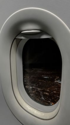 an airplane window looking out at the city lights and water from inside one plane's cabin