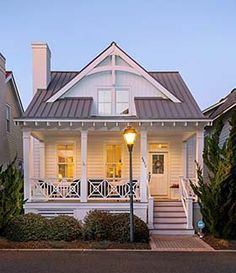 a white house with porches and stairs leading up to the front door at dusk