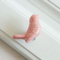 a pink bird figurine sitting on top of a white door