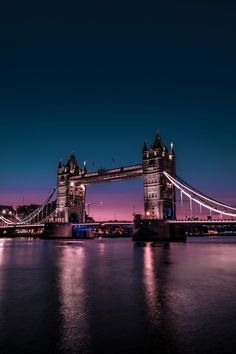 the tower bridge is lit up at night