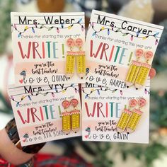 two handmade earrings with writing on them are being held in front of a christmas tree