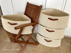 two baskets sitting next to each other on the floor in front of a chair and door