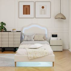 a white bed sitting in a bedroom next to two pictures on the wall above it