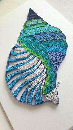 a blue and green fish with intricate designs on it's body is sitting on a piece of paper