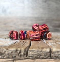 an assortment of colorful bracelets sitting on top of a piece of wood next to each other