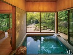 an indoor swimming pool in the middle of a room with large glass doors and windows