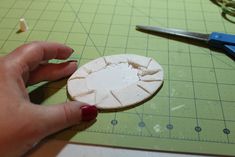 a person is making a paper flower with scissors on a cutting board next to it