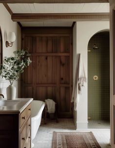 a bath room with a tub a sink and a rug on the floor in front of it