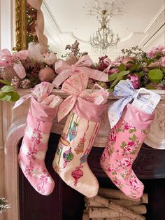 two christmas stockings hanging from a fireplace mantel with pink flowers and bows on them